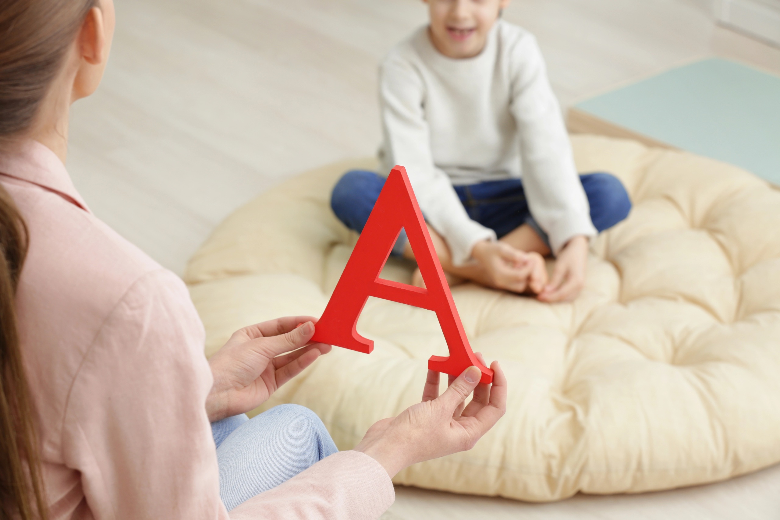 Erwachsener zeigt Kind roten Buchstaben A
